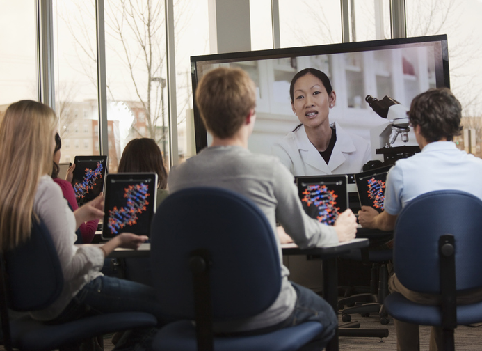 Students with digital tablets watching instructor on monitor